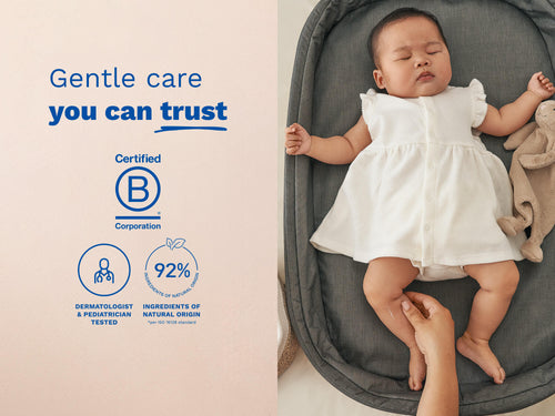 Baby lying on a gray cushioned lounger wearing a white outfit, with a hand gently touching the baby’s leg and text on the left side of the image - Mustela USA - 5