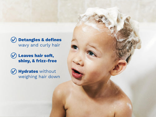 Child taking a bath with shampoo foam in their curly hair, next to text highlighting detangling, softening, and hydrating benefits. - Mustela USA - 2