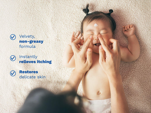 Caregiver applying soothing face cream to smiling baby. - Mustela USA - 2