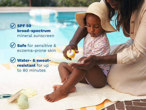 Mustela USA | Mother applying Mustela SPF 50 mineral sunscreen on her toddler's legs by a pool. Key benefits: broad-spectrum SPF 50, safe for sensitive and eczema-prone skin, water- and sweat-resistant up to 80 minutes. - Mustela USA - 2