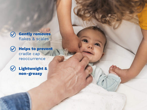 Smiling baby lying on a bed while two adults gently touch their face and hold their hand, with blue text on the left side. - Mustela USA - 4