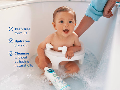 Mustela USA | Smiling baby sitting in a bath seat holding a bottle of cleansing gel. - Mustela USA - 4