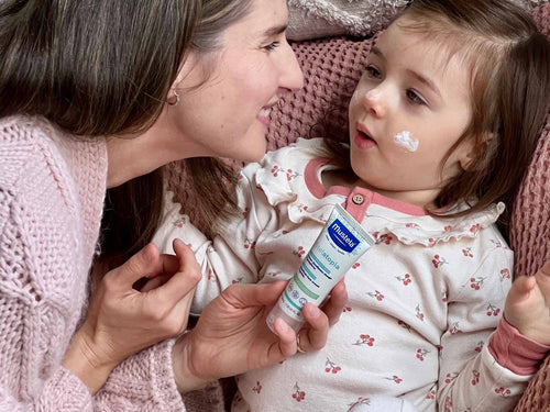 Mother applying Stelatopia Emollient Face Cream on girl's face - Mustela USA - 3