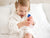 Image of little girl dressed in robe squeezing Soothing Moisturizing Face Cream product onto leg